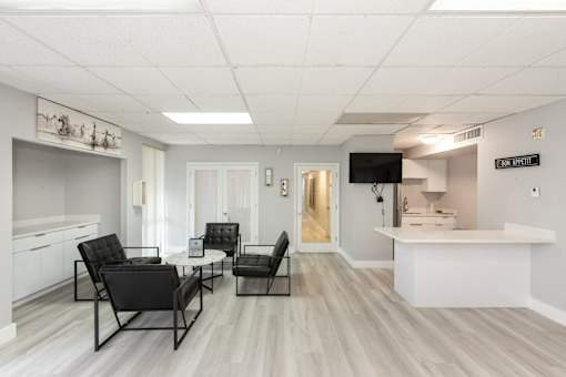 A well-lit room with a black chair and a white counter.