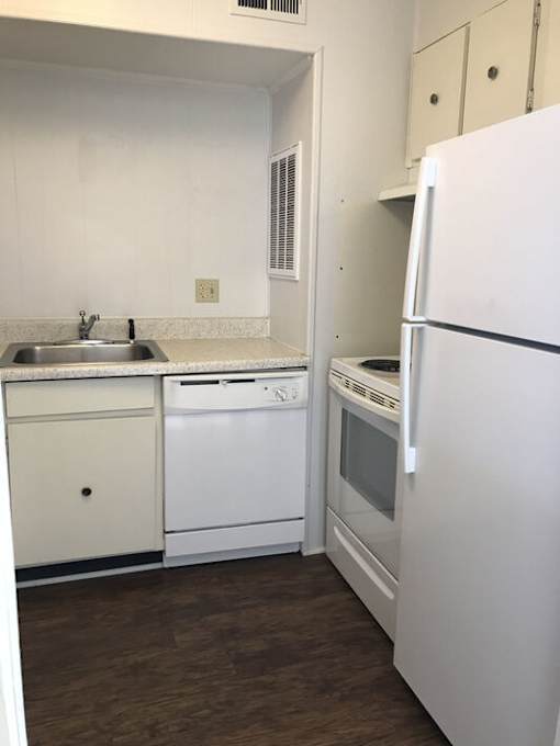 A white kitchen with a white fridge and white cabinets.