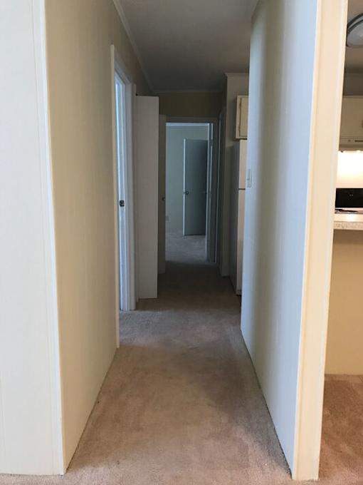 A hallway with a carpeted floor and white walls.