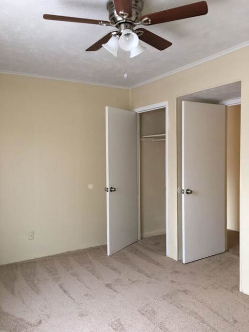 A room with a ceiling fan and two doors.