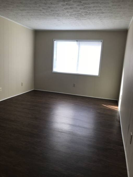 A room with a window and wooden flooring.