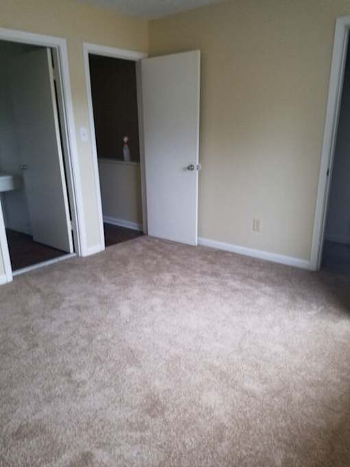 A carpeted room with a white door and a white cabinet.