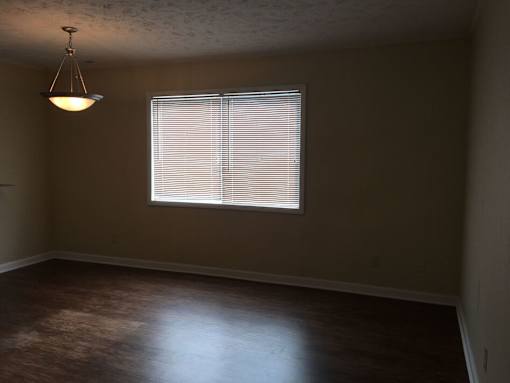A room with a window covered by blinds and a hanging light fixture.