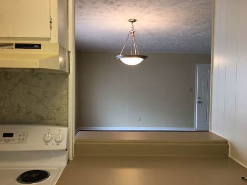 A kitchen with a stove and a hanging light fixture.
