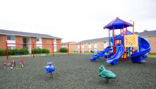 A playground with a blue slide and a red and blue playhouse.