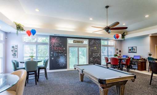 A room with a pool table and a chalkboard wall.