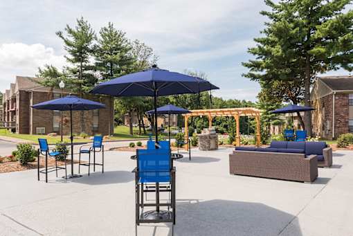 A blue chair sits under a blue umbrella in a courtyard.