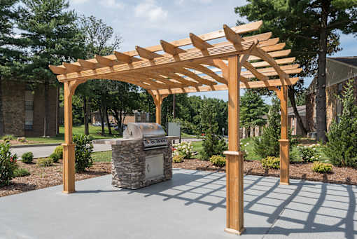 A wooden pergola is over a stone fireplace.