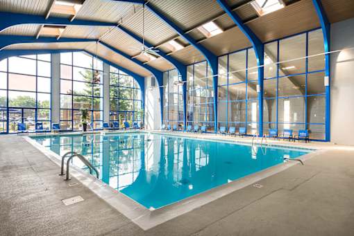 A large indoor swimming pool with a glass wall on one side.