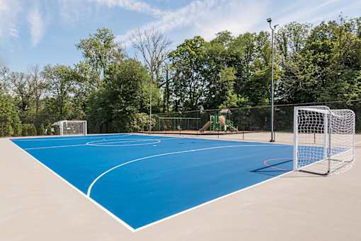 A blue outdoor basketball court with a goal post on the right side.