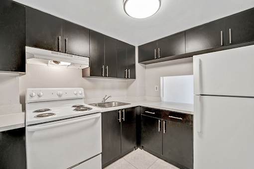 A kitchen with black cabinets and white appliances.