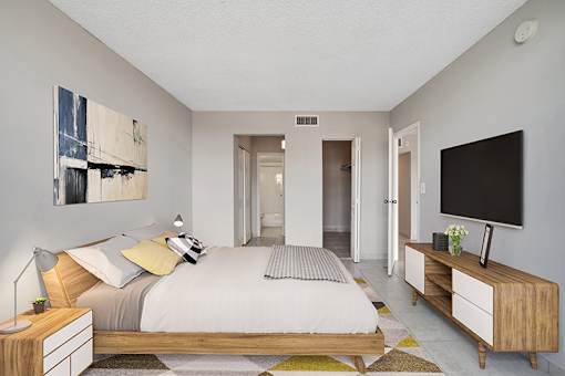 A bedroom with a bed, nightstand, and a television.
