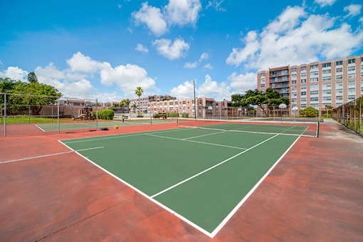 A tennis court with a red surface and white lines.