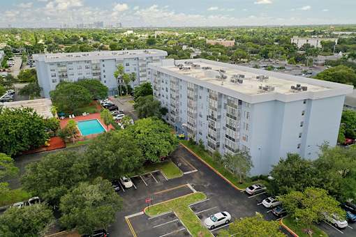 A large white apartment building with a pool in the courtyard.