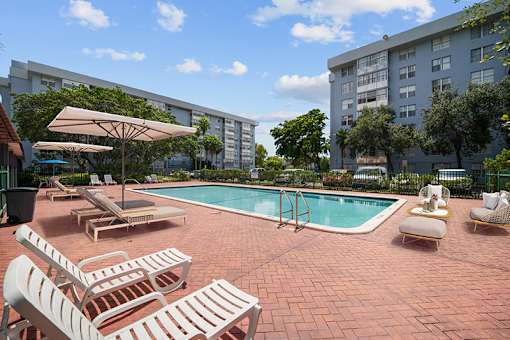 A pool area with sun loungers and a white umbrella.