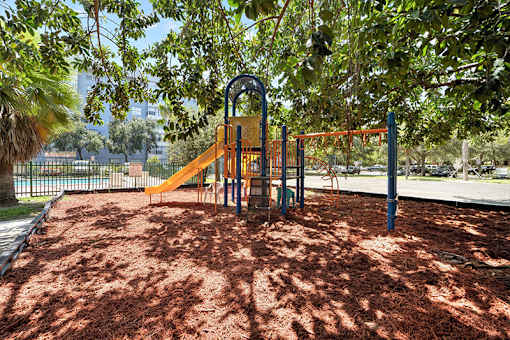 A playground with a yellow slide and a red swing set.