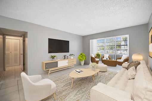 A living room with a white sofa, a wooden coffee table, and a flat-screen TV mounted on the wall.