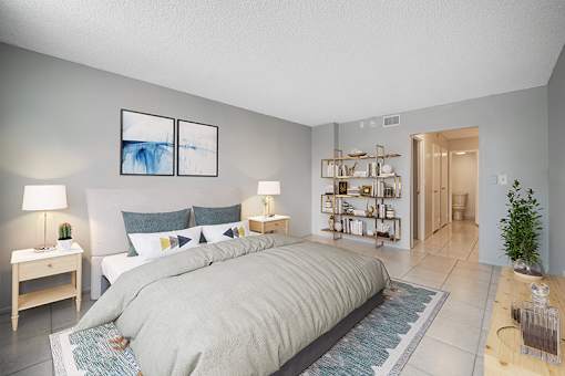 A bedroom with a large bed and a small table with a lamp on it.