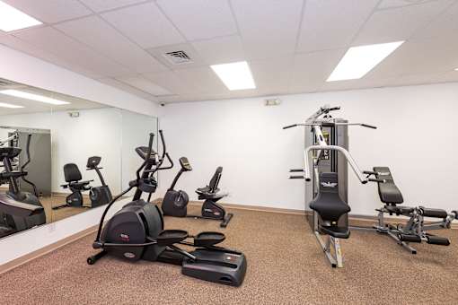 A gym room with exercise equipment and a mirror.