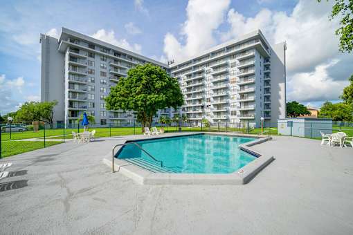 A large apartment complex with a pool in the foreground.