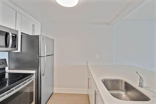 A kitchen with a sink, refrigerator, and microwave.
