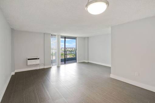A spacious room with a sliding glass door leading to a balcony.