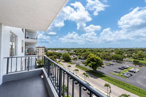 A balcony overlooks a parking lot and a street.
