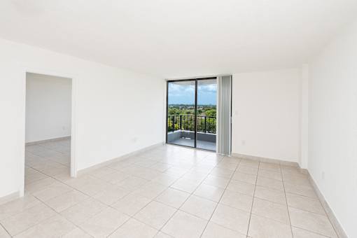 A large empty room with a sliding glass door leading to a balcony.