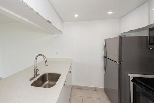 A kitchen with a sink and a refrigerator.