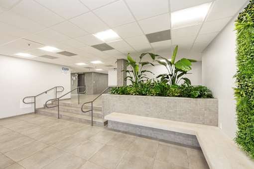 A green plant wall in a white room with a staircase.