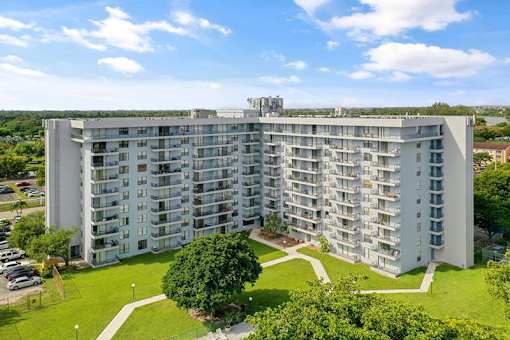A large white apartment building with a green lawn in front.