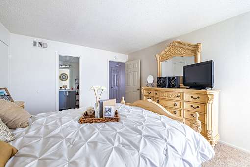 A bedroom with a bed, dresser, and mirror.