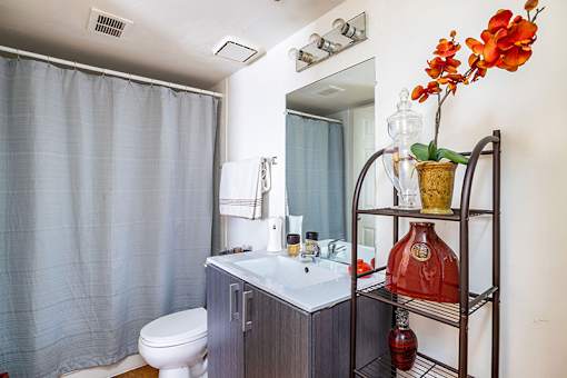 A bathroom with a toilet, sink, and a shelf with a vase of flowers.