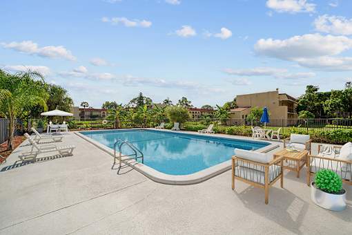 A pool with a slide and chairs around it.