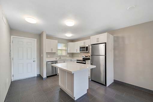 A modern kitchen with a white island and stainless steel appliances.