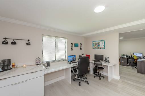 A well-lit office space with two desks and chairs.