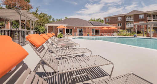 A pool surrounded by orange sun loungers and a building in the background.