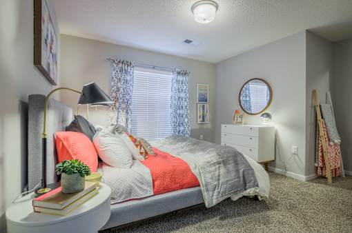 A bedroom with a bed, nightstand, and a window with curtains.