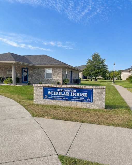 A sign for Bowling Green Scholar House stands in front of a building.