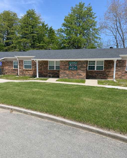 A small brick building with a green sign on the front.