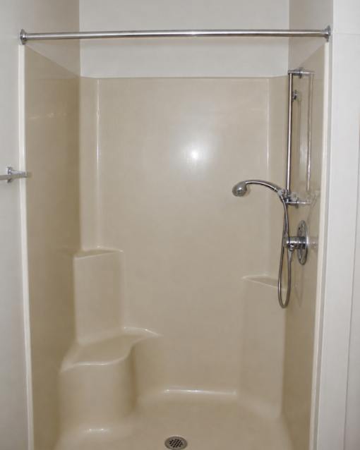 A white shower stall with a glass door and a shower head.