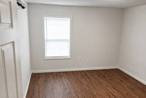 A room with a window and wooden flooring.
