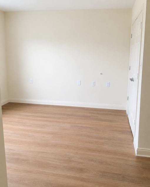 A room with light wood flooring and white walls.