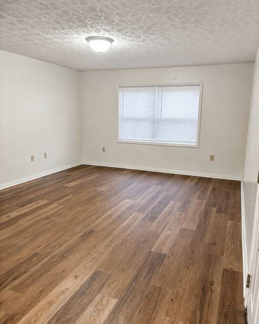 A room with wooden flooring and a window.