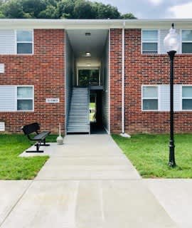 A brick building with a black bench in front of it.