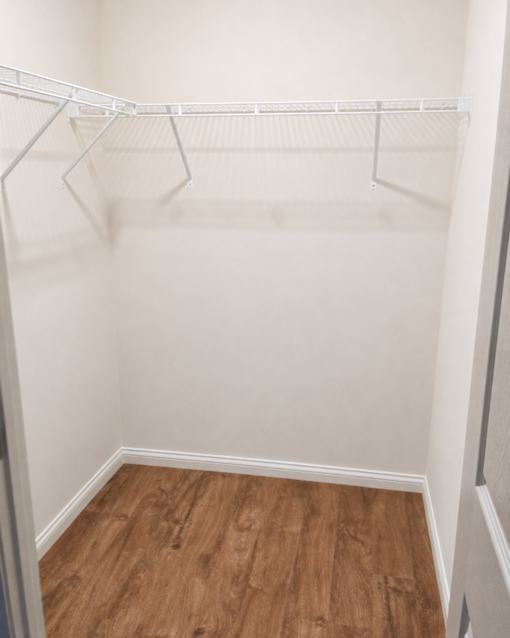 Empty white closet with wood floors.