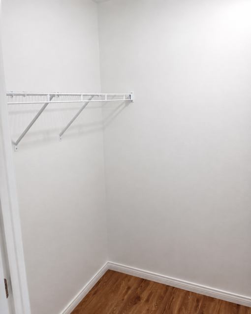 A white closet with a shelf and a door.