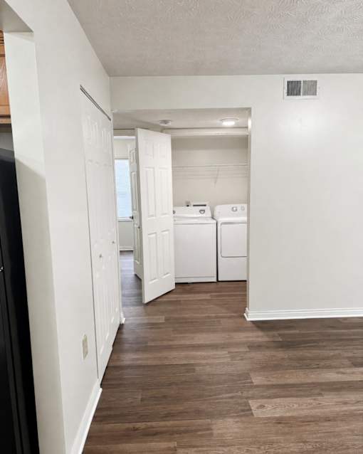 A kitchen with white appliances and wood floors.