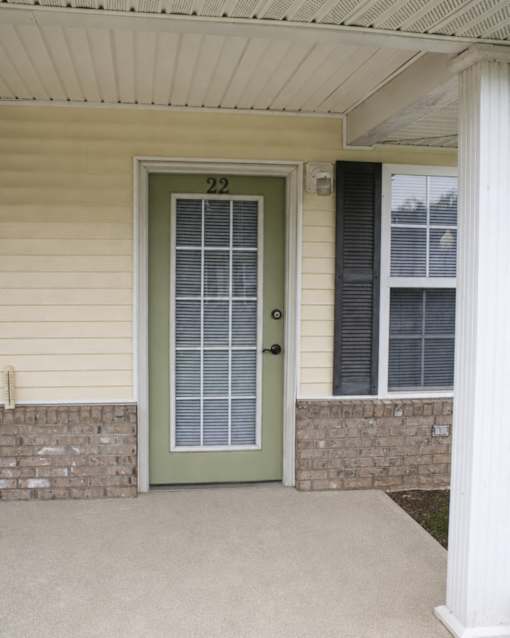 A house numbered 22 with a green door and a brick wall.