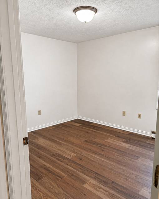 A room with wooden flooring and white walls.
